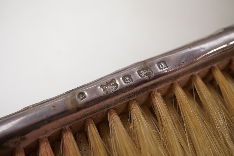 Four assorted early 20th century repousse silver mounted dressing table items to include a hand mirror, two hair brushes and a clothes brush(a.f.).